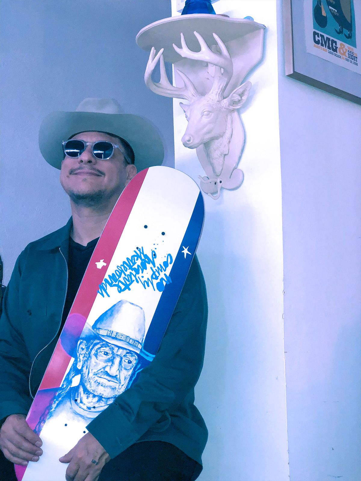 Portrait of Carlos M. Gutierrez behind his Willie board made for No Comply Skateshop in Austin, TX
